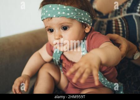 Mère tenant les mains bébé fille avec un bandeau sur sa tête. Gros plan portrait. Banque D'Images