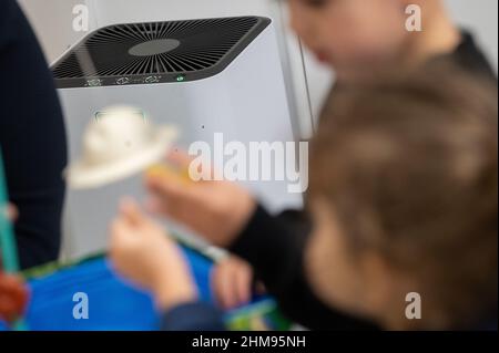 PRODUCTION - 02 février 2022, Hessen, Darmstadt : un purificateur d'air se tient derrière un éducateur et des enfants dans une garderie. Photo: Sebastian Gollnow/dpa Banque D'Images