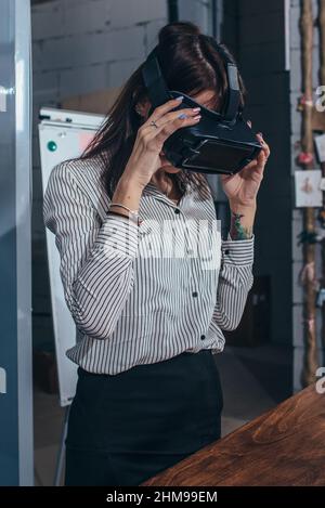 Les travailleuses de bureau s'amusent au travail en regardant 3D vidéos dans des lunettes VR, une femme touchant quelque chose en train de vivre la réalité virtuelle. Banque D'Images