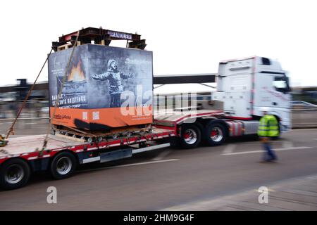 Une caisse contenant les Greetings de la saison par l'artiste de rue Banksy quitte une unité de vente au détail à Ty'r Orsaf, Port Talbot, alors qu'elle se déplace vers une unité de stockage temporaire à un emplacement non divulgué après des tentatives de « fanatiques » pour endommager l'œuvre. Date de la photo: Mardi 8 février 2022. Banque D'Images