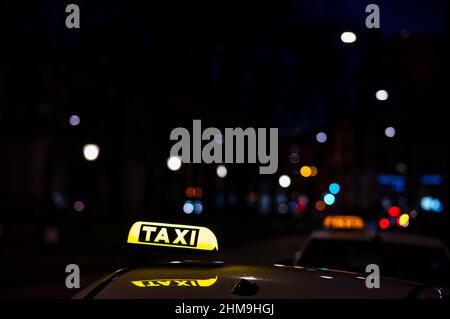 Panneau de taxi allemand la nuit, éclairé par les lumières de la ville en arrière-plan Banque D'Images