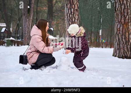 Une mère attentionnée met des gants sur son enfant un jour d'hiver Banque D'Images