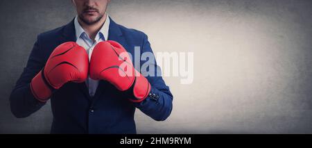 Gros plan homme d'affaires en costume avec des gants de boxe rouges se tient prêt dans une position de combat, pointant ses poings. Concept d'auto-défense de la personne d'affaires, isola Banque D'Images