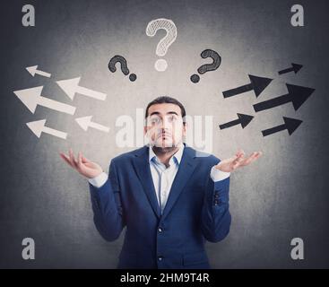 Un homme d'affaires perplexe hausse les épaules, les mains tendues, a des doutes pour choisir le côté gauche ou droit. Les hommes perplexes expriment de l'incertitude, a des questions A. Banque D'Images