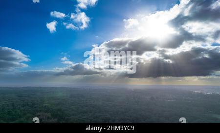 Le soleil d'hiver qui se brise à travers les nuages illumine les arbres et les champs gelés dans le froid avec sa faible lumière. Photo de haute qualité Banque D'Images