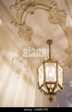 Depuis le dessous d'un lustre vintage brillant suspendu sur une chaîne de plafond blanc avec des éléments décoratifs dans la salle lumineuse à la maison Banque D'Images