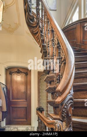 Escalier en bois avec balustrade ornementale placé dans le couloir avec des vêtements accrochés sur un rack dans un appartement lumineux avec des fenêtres à la maison Banque D'Images