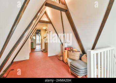 Valises près des étagères avec divers récipients et sac placés dans un grenier clair avec plancher rouge et fenêtre dans l'appartement Banque D'Images