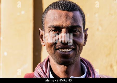 Portrait d'un homme égyptien adulte heureux avec un sourire éclatant et des yeux bruns regardant l'appareil photo le jour ensoleillé de la ville Banque D'Images