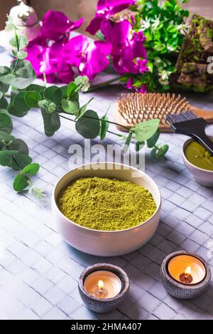 De la composition ci-dessus avec un bol de henné en poudre mort près du peigne en bois de brosse et des bougies en feu pour les soins naturels des cheveux Banque D'Images