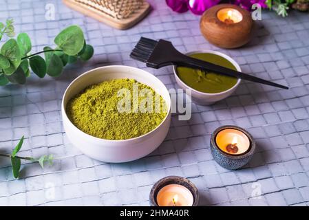 De la composition ci-dessus avec un bol de henné en poudre mort près du peigne en bois de brosse et des bougies en feu pour les soins naturels des cheveux Banque D'Images