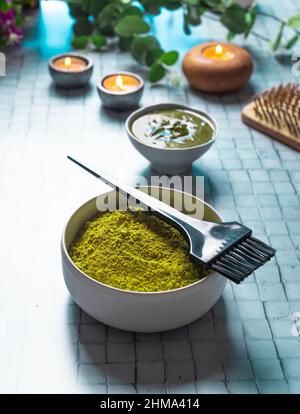 De la composition ci-dessus avec un bol de henné en poudre mort près du peigne en bois de brosse et des bougies en feu pour les soins naturels des cheveux Banque D'Images