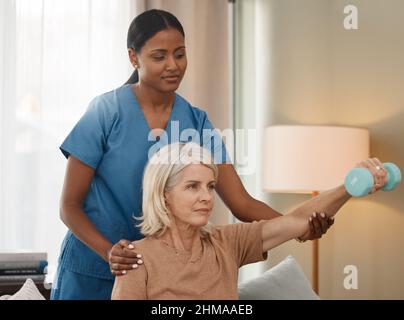 Vivre une vie meilleure avec chaque ascenseur. Prise de vue d'une femme âgée utilisant des haltères pendant un examen avec son médecin à la maison. Banque D'Images