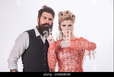 Homme hippster sérieux avec barbe et femme avec ciseaux. Coiffeur. Belle femme coupe la barbe. Couple dans un salon de coiffure sur fond isolé. Banque D'Images