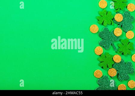 Feuilles de trèfle et pièces de monnaie faites à la main sur fond plat en tissu vert Banque D'Images