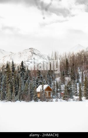 Petite cabane en forêt sur le côté du lac gelé en Alaska Banque D'Images