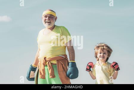 Plus âgé - jeune homme boxe. Beau homme âgé pratiquant des coups de pied de boxe. Entraîneur senior et petit garçon portant des gants de boxe. Banque D'Images