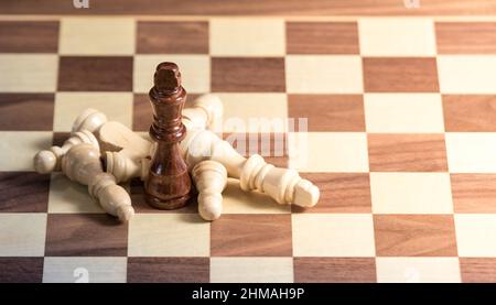 Pièces d'échecs déchus autour d'un roi sur un plateau d'échecs. Lumière du côté droit Banque D'Images