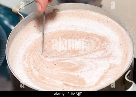 Mélange du chocolat et du lait pour préparer des souffleurs. Gros plan. Banque D'Images