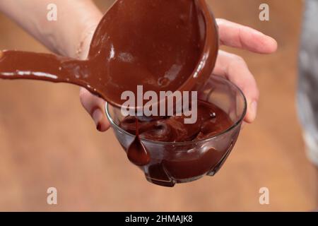 Verser le chocolat noir fondu dans un bol en verre. Gros plan. Banque D'Images