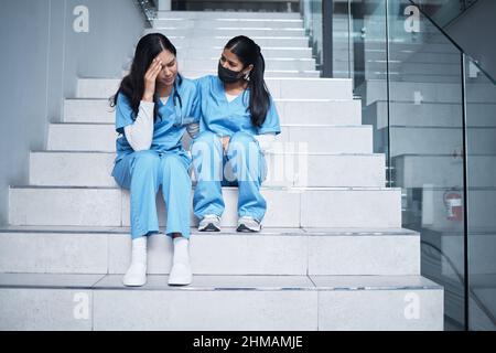 Nous avons fait de notre mieux. Photo d'une infirmière qui réconforte sa collègue en s'asseyant dans un escalier au travail. Banque D'Images