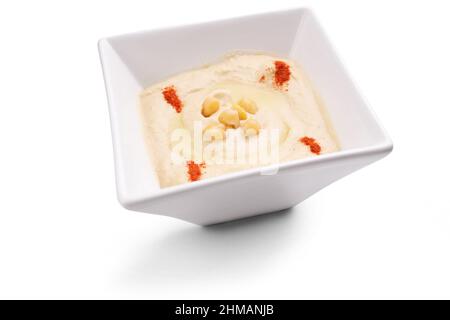 Humus à trempette arabe dans un bol blanc décoré de pois chiches et de paprika isolés sur fond blanc Banque D'Images