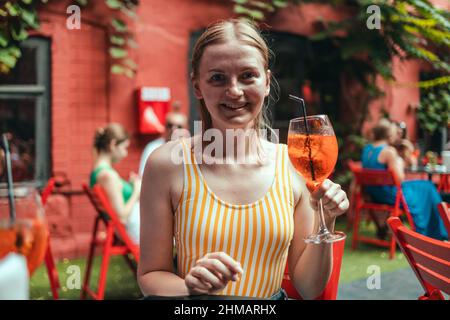 Bonne femme avec un verre de cocktail glacé aperol Spritz au restaurant. Banque D'Images