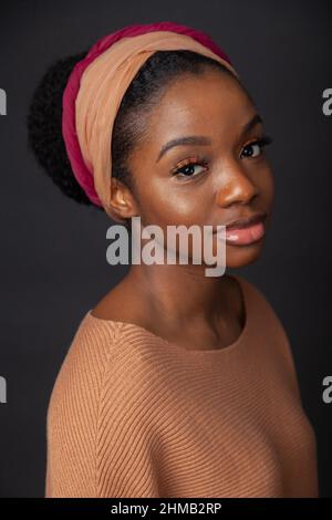Un portrait rapproché d'une femme noire avec ses cheveux attachés et portant et serre-cheveux. Banque D'Images