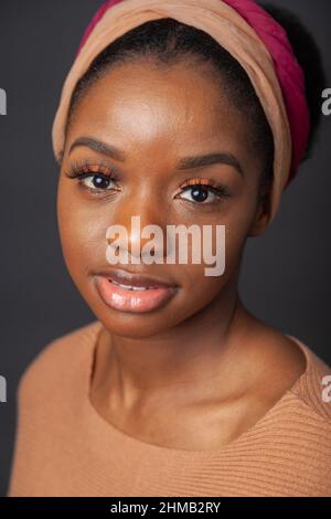 Un portrait rapproché d'une femme noire avec ses cheveux attachés et portant et serre-cheveux. Banque D'Images