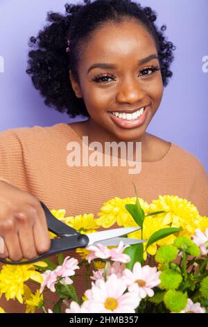 Une jeune femme noire britannique tenant une paire de ciseaux sur des fleurs Banque D'Images