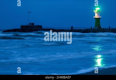 05 février 2022, Mecklembourg-Poméranie occidentale, Warnemünde : le phare de l'une des jetées à l'entrée du canal maritime de Rostock clignote dans la soirée. Le temps sec et froid de l'hiver attire encore les vacanciers et les visiteurs de jour à la plage même après le coucher du soleil, malgré le vent féroce. Photo: Jens Büttner/dpa-Zentralbild/ZB Banque D'Images