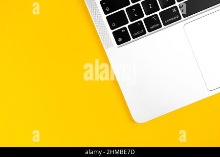 Ordinateur portable moderne, plat, fond jaune. Clavier pour ordinateur portable. Table de bureau, concept de conception minimal. Vue de dessus, espace de copie Banque D'Images
