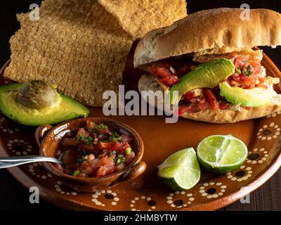 Bolillo farci de chicarron, d'avocat et de sauce mexicaine (Guacamaya). Banque D'Images