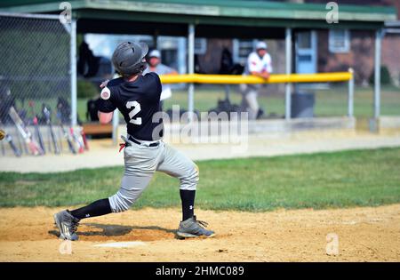 Johnsburg, Illinois, États-Unis. Un batter suit après avoir balançoire sur un terrain lors d'un match de baseball amateur pour hommes dans le nord-est de l'Illinois. Banque D'Images