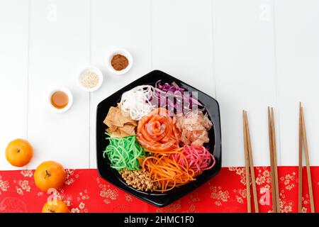 Yusheng, Yee a chanté ou yuu sahng, ou Prosperity Toss ou Lo Sahng. Placé sur une plaque noire et une table surfacée blanche avec des décorations chinoises rouges. Copier Spac Banque D'Images