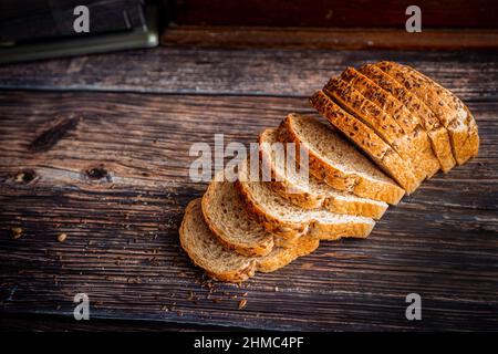 Pain de graines de lin de blé entier fraîchement cuit coupé en tranches sur une table en bois rustique avec espace de copie. Banque D'Images