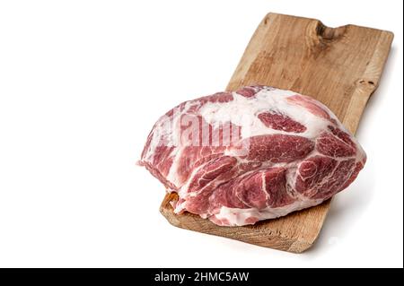 Hacher l'épaule de porc crue sur une planche de bois isolée sur blanc. Steak de porc non cuit. Morceau de viande rouge fraîche sur la boucherie, marché. Banque D'Images