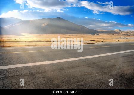Photo panoramique d'une route vide au milieu d'un champ de plaine sec Banque D'Images