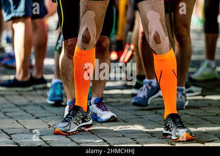 jambes de coureur de sexe masculin en chaussettes de compression et de ruban kinesio sur les genoux Banque D'Images