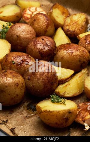 Pomme de terre cuite épicée dans un plateau avec du romarin et de l'ail sur une couche de parchemin Banque D'Images