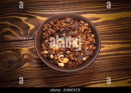 Céréales granola au chocolat avec noix dans un bol sur fond de bois. Banque D'Images