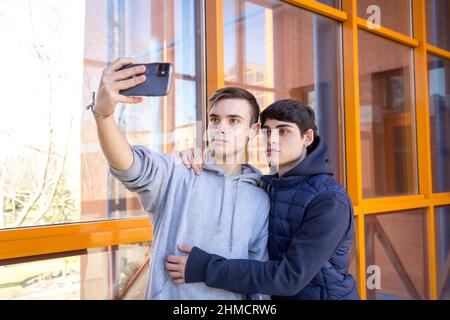 deux amis d'université gay prenant une photo avec un téléphone cellulaire Banque D'Images