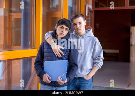 deux jeunes étudiants de l'université qui s'embrasent en posant tout en regardant la caméra Banque D'Images