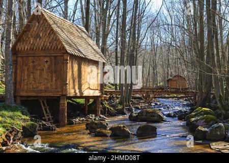 Belles cabanes en rondins au bord d'un ruisseau dans la forêt et passerelle au-dessus de l'eau Banque D'Images