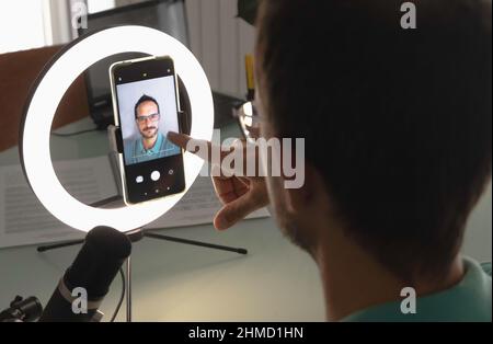 un homme qui a configuré un appel vidéo avec son smartphone et une lampe studio à anneau lumineux Banque D'Images