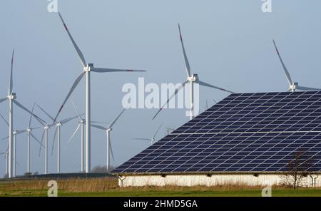 PRODUCTION - 07 février 2022, Schleswig-Holstein, Reußenköge: Les éoliennes se tiennent à côté d'un hall avec des systèmes photovoltaïques sur le toit. Photo: Marcus Brandt/dpa Banque D'Images