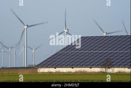 PRODUCTION - 07 février 2022, Schleswig-Holstein, Reußenköge: Les éoliennes se tiennent à côté d'un hall avec des systèmes photovoltaïques sur le toit. Photo: Marcus Brandt/dpa Banque D'Images