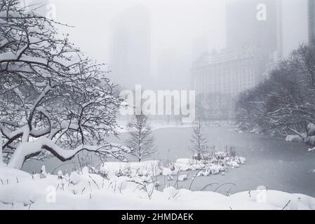 Neige à Central Park, New York. Fortes chutes de neige hivernales. Le lac à Midtown Manhattan. Brouillard. Le Plaza Hotel et la Cinquième Avenue. Météo hivernale. ÉTATS-UNIS Banque D'Images