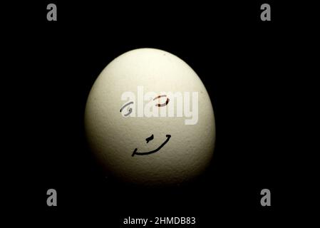 L'œuf représente le visage humain du sourire isolé sur fond noir Banque D'Images