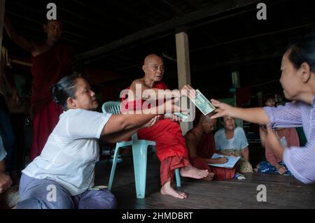 Le moine bouddhiste donner de l'argent aux personnes touchées par le cyclone dans un monastère de Kyauktan canton de Yangon Myanmar, Birmanie 15 Mai 2008 Banque D'Images